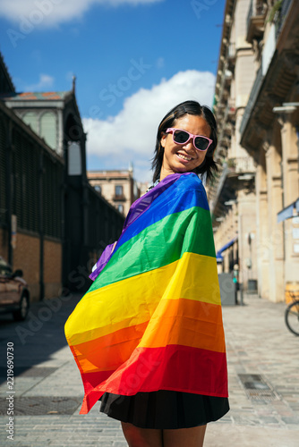 Young woman embracing lgbt pride flag on city street