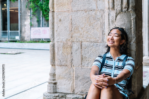 Young woman smiling, daydreaming in historic stone courtyard
