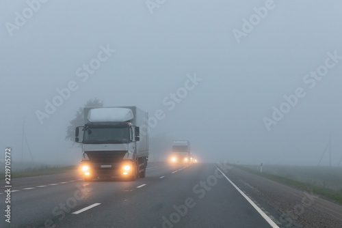 Truck on a country road in the thick fog. Poor visibility conditions on the road.