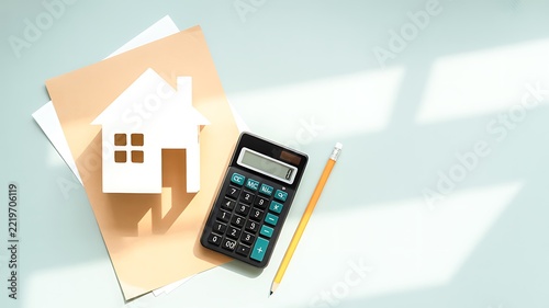 House model with calculator and pencil representing real estate finance and home budget planning