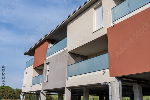 Building facade with balcony glass railing red render and small window