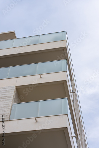 Low angle view of concrete balcony slab and glass railing against sky