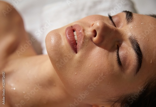 Woman relaxing with closed eyes during a luxurious spa facial treatment
