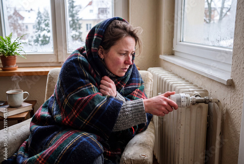 Woman feeling cold turning up heating thermostat