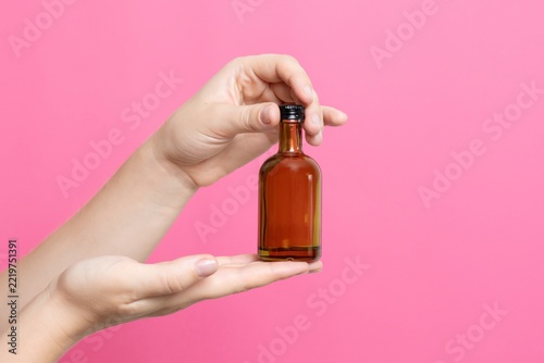 Hand presenting small amber bottle filled with alcohol