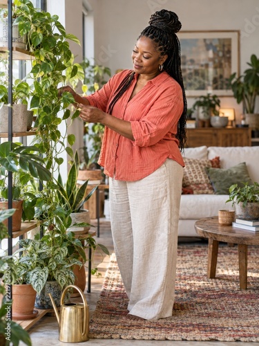 Woman tending trailing houseplants beside a window on a quiet morning