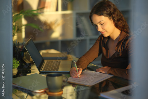 Telecommuter at sunset working filling out form at home