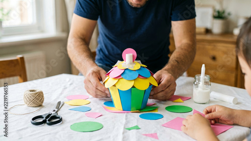 Child arranges bright geometric construction pieces on a pastel tabletop while using craft materials to create a playful model and discover simple shape patterns