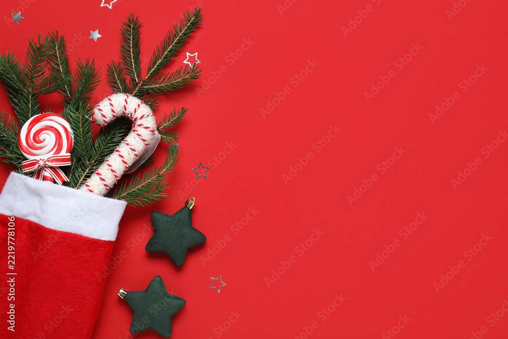 Fototapeta premium Christmas celebration and holiday spirit, festive stocking with candy canes and pine branches on a red background with copy space for seasonal greeting