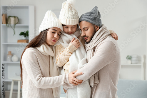 Ill family in warm hats hugging at home