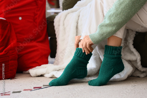 Woman in warm green socks at home on Christmas eve, closeup