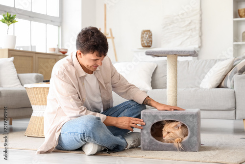 Pet companionship and mental health, young man playing with his fluffy cat in...