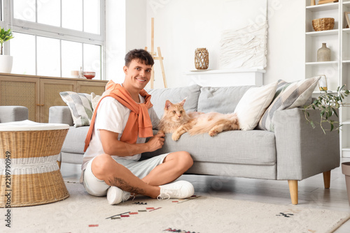 Pet ownership and companionship, happy young man sitting on floor with fluffy...