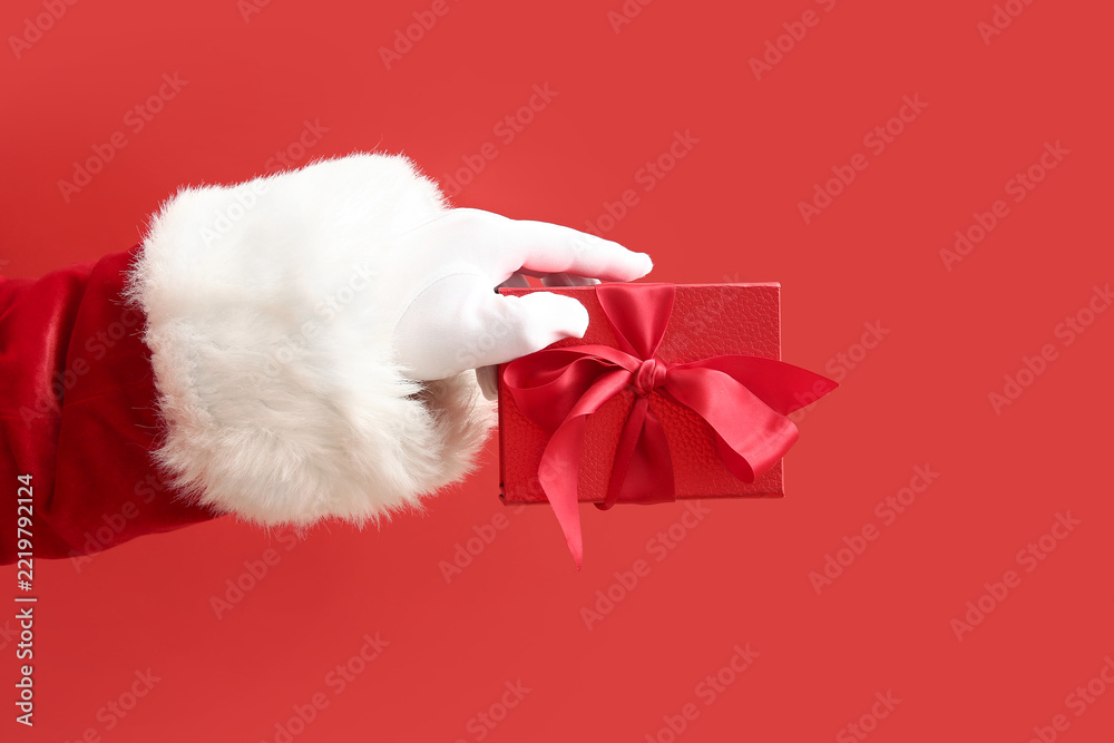 Fototapeta premium Santa Claus with red gift box on color background