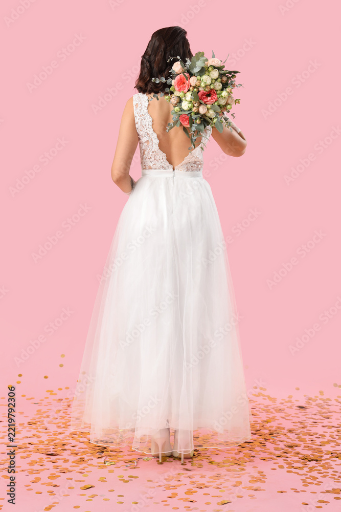 Fototapeta premium Wedding celebration and bridal joy, bride in white lace dress holding floral bouquet with gold confetti on pink background for marriage ceremony