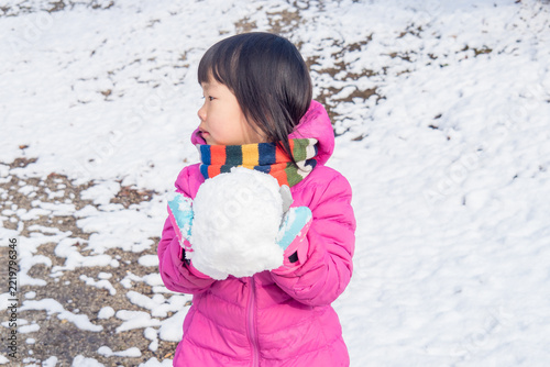 冬の雪が降る公園で楽しく雪遊びしている幼児の子供の様子
