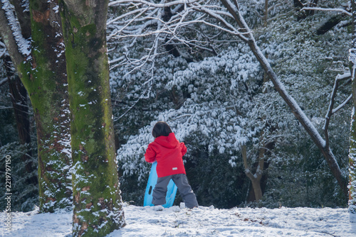 冬の雪が降る公園で楽しく雪遊びしている幼児の子供の様子
