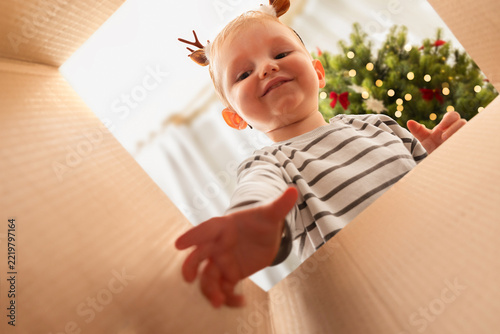 A happy child reaching into a box for gifts or Christmas decorations. Low-angle view. Concept of delivery and family traditions.