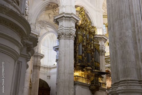 Golden pipe organ among massive columns in Granada Cathedral