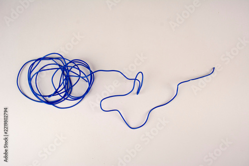 a tangled mess of thin blue string lies on a plain white surface, with a loose end trailing off to the right