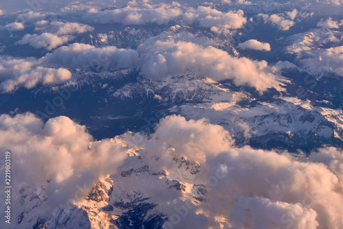 Pink evening clouds over snow covered mountain range, aerial