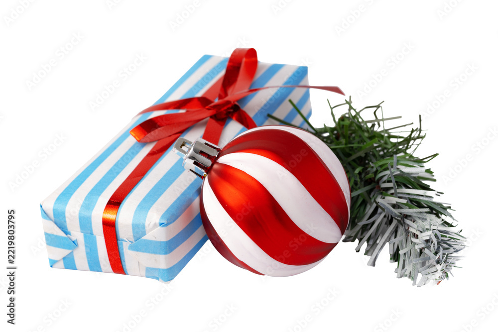Fototapeta premium Christmas gift box with striped wrapping and a red and white ornament beside a sprig of greenery