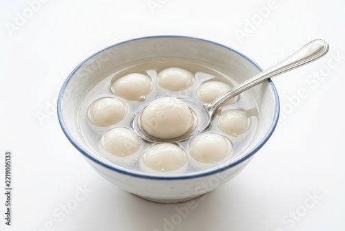 Traditional Chinese Tangyuan Glutinous Rice Balls in a Ceramic Bowl with Spoon Isolated on White Background