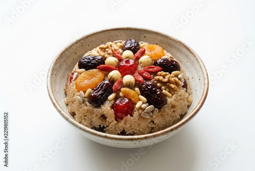 Traditional Chinese Eight-Treasure Rice Pudding with Dried Fruits and Nuts in a Ceramic Bowl on White Background