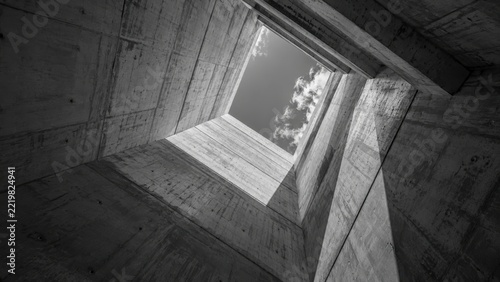 Modern architectural concrete structure with a sky view from within a deep square opening