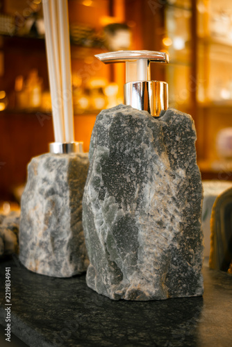 Rustic stone soap dispensers on a dark granite countertop, combining natural textures, elegant design, and warm bathroom ambiance.