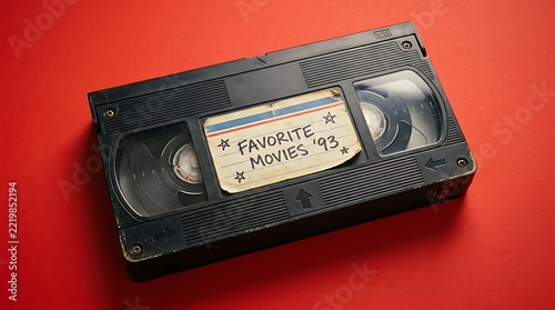 Vintage black VHS tape with a handwritten label on a vibrant red background for retro nostalgia