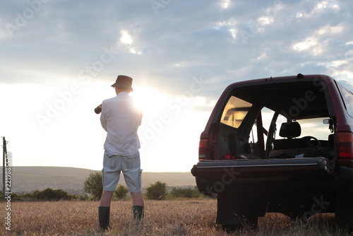 Man takes photographs in a field during sunset.