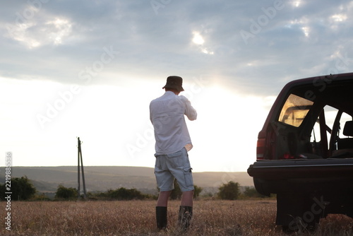 Man takes photographs in a field during sunset.