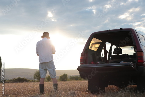 Man takes photographs in a field during sunset.