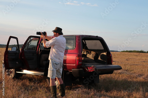 Man takes photographs in a field during sunset.