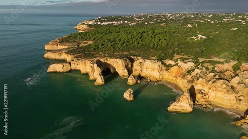 Aerial view of Praia da Marinha beach in Algarve, Portugal, with ocean cliffs, sea stacks and coastal cove shapes. Orbit parallax shot.