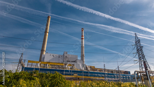 Industrial power plant with tall chimneys and high voltage transmission lines under blue sky in Eastern Europe, Varna, Bulgaria