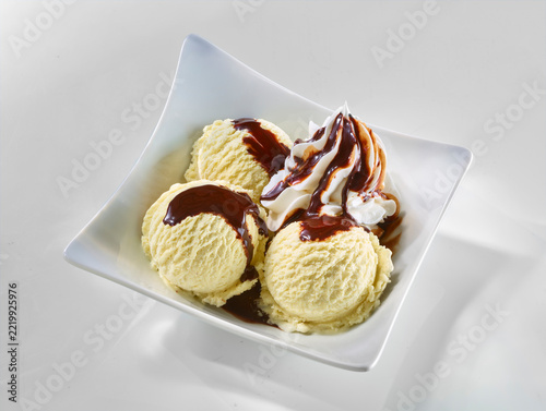 Drei Kugeln Vanilleeis mit Schokoladensauce und Sahnehaube