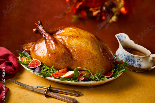 Roasted Thanksgiving turkey served with figs and apples on an orange brown background. Close up.