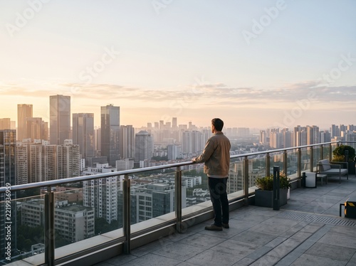 Professional man enjoying sunset view from urban rooftop terrace with