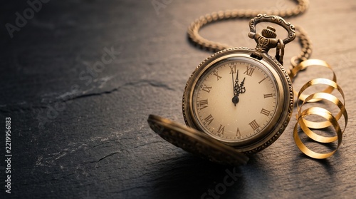 Vintage brass pocket watch with chain, elegant antique timepiece on dark slate, classic clock for history and time concepts, old-fashioned golden accessory for countdowns and deadlines