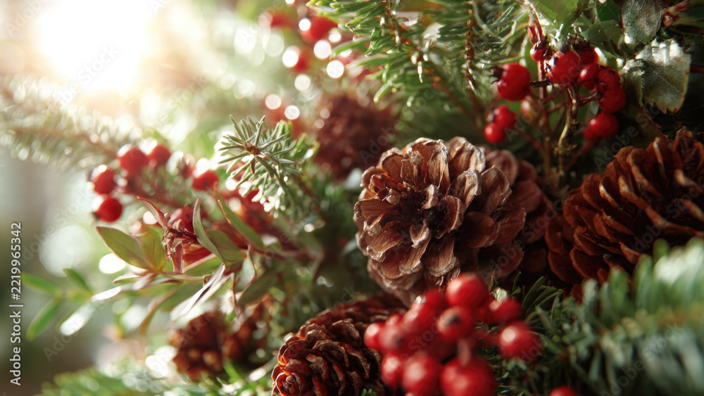 Fototapeta premium Festive winter arrangement with pinecones and red berries against a blurred background