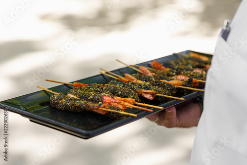 Waiter carrying a tray of shrimp skewers at a corporate event