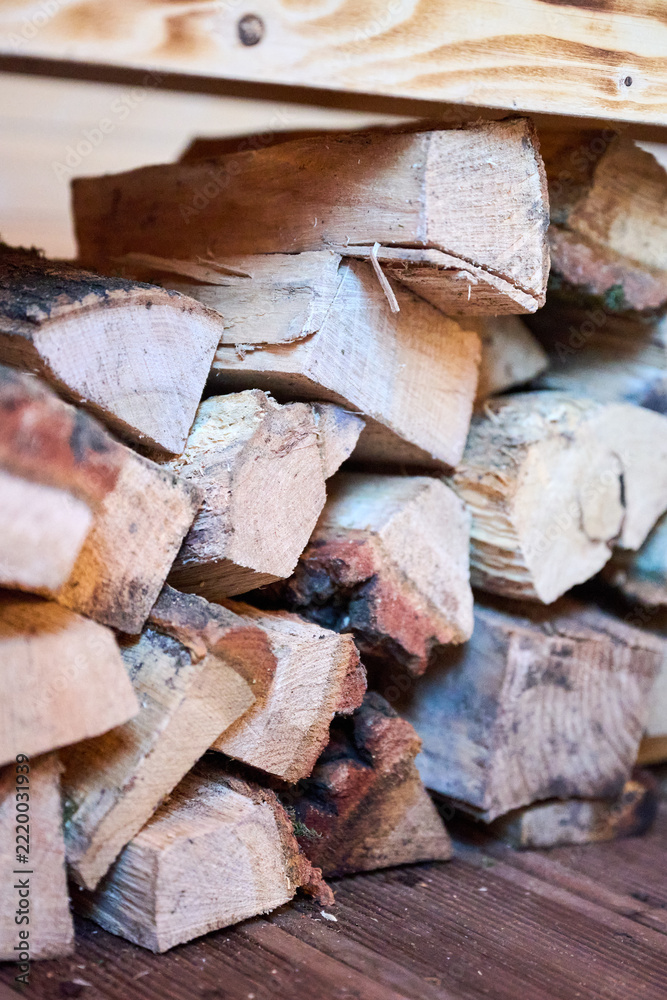 Naklejka premium Stacked firewood stored under wooden bench inside sauna room. Close up