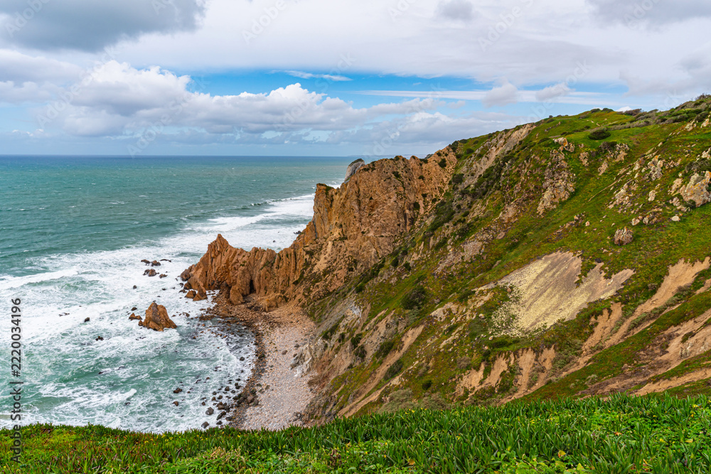 Fototapeta premium Cabo da Roca dramatic coastal cliff overlooking Atlantic Ocean in Portugal. Scenic westernmost point of Europe with rugged landscape, ocean waves and natural coastline.