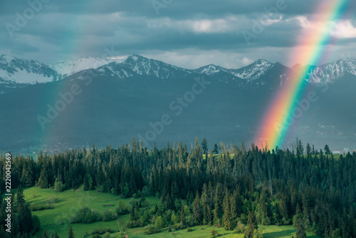 Majestic panoramic view of the Tatra Mountains landscape featuring snow-capped peaks, colorful forests, and picturesque valleys under a dramatic sky. Beautiful scenic nature and wilderness background