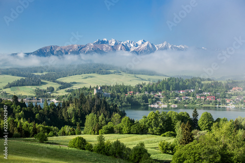 Majestic panoramic view of the Tatra Mountains landscape featuring snow-capped peaks, colorful forests, and picturesque valleys under a dramatic sky. Beautiful scenic nature and wilderness background