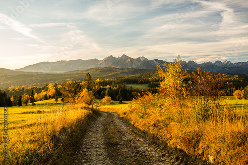 Majestic panoramic view of the Tatra Mountains landscape featuring snow-capped peaks, colorful forests, and picturesque valleys under a dramatic sky. Beautiful scenic nature and wilderness background