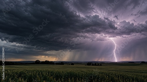 Distant Lightning Illuminating Layered Storm Clouds Above Open Fields