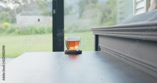 Double-walled cup is releasing steam as it cools, wisps drifting left near sliding glass door